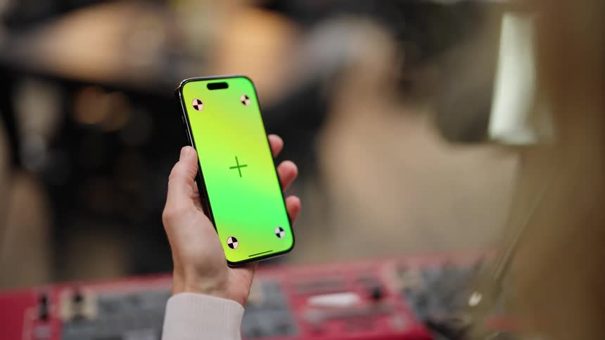 A woman is holding a phone with a green screen and pushing her finger on the screen