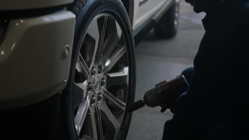 A man removes lug nuts from a car wheel