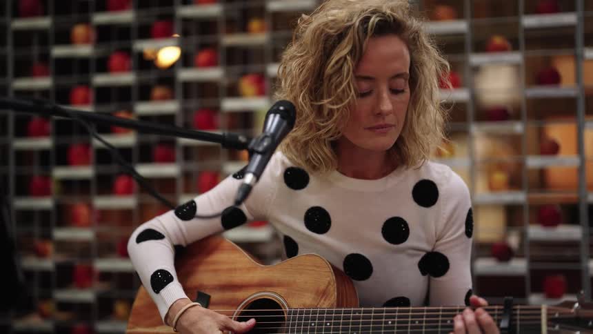 A woman gets ready to play guitar during a performance