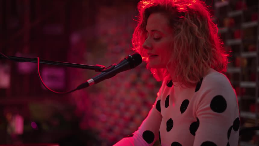 A woman sings as she plays a keyboard