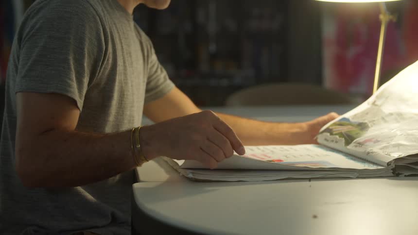 A man sits in an office and flips through a book with photos