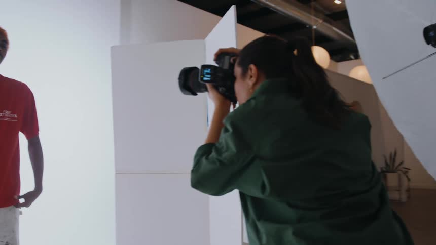 A woman takes photos of a man during a photo shoot