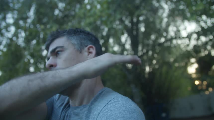 Man stands in back yard patting his arm and body
