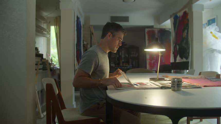 A man flips through a scrapbook while sitting at home