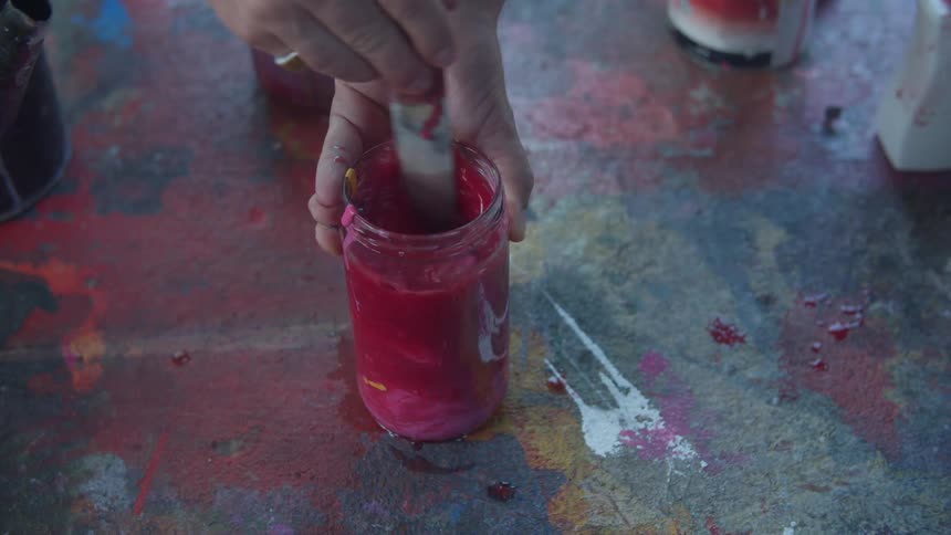 A woman is stirring something inside of a glass on a table