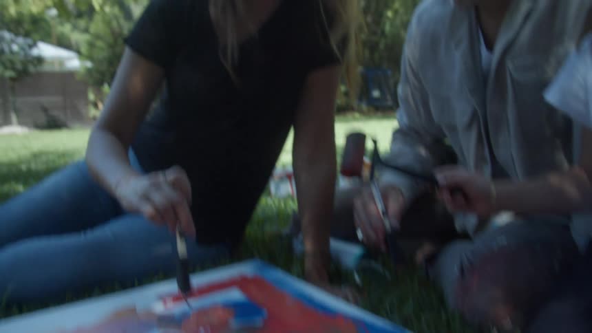 A girl paints in the a back yard with her mother and father