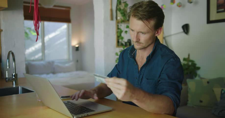 A man is inputting his credit card information into a laptop