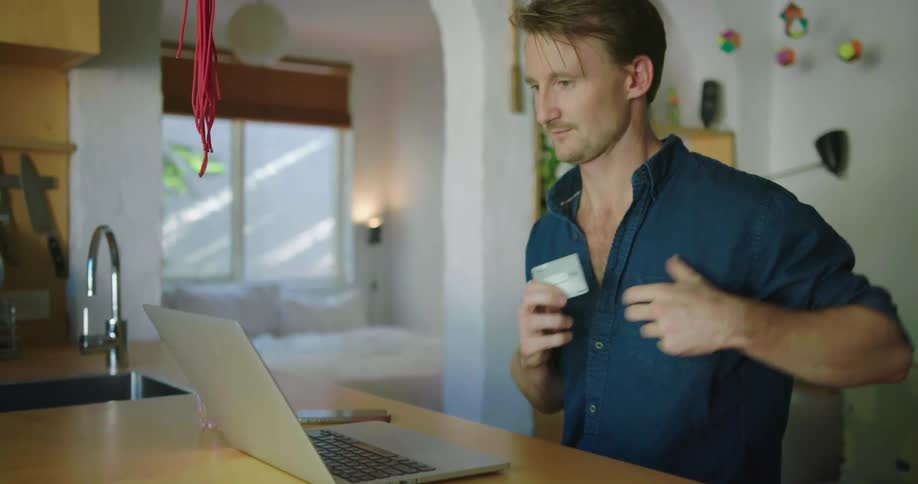 A man is inputting his credit card details into a laptop