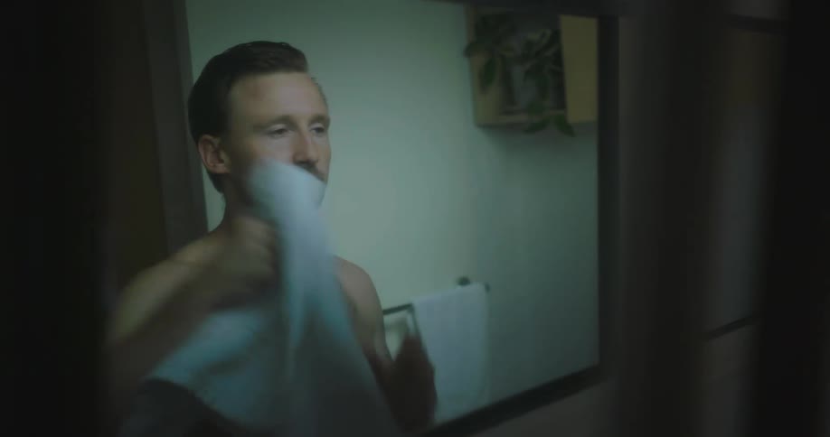 A man is washing and drying his face in the bathroom