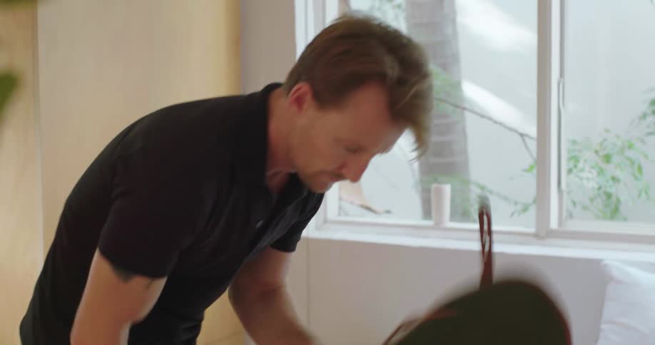 A man packing a duffel bag looks around his room