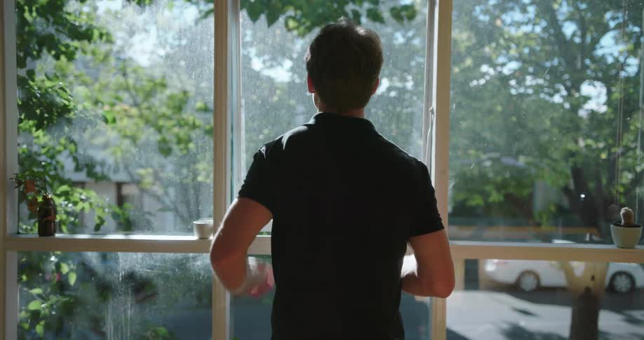 Man looks out a large window on a sunny day