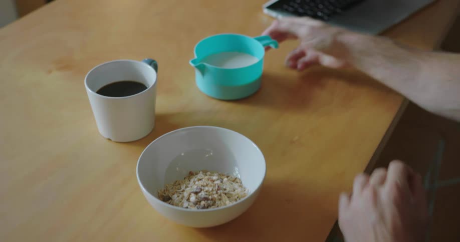 A man pours cereal and milk into a bowl