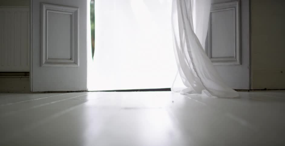 Curtains blow in front of a doorway