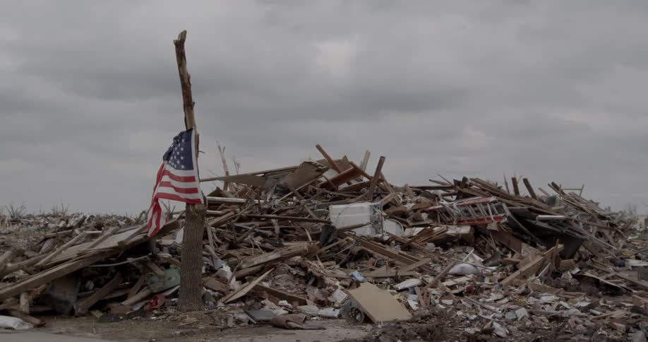 An american flag is hanging in front of a demolished home