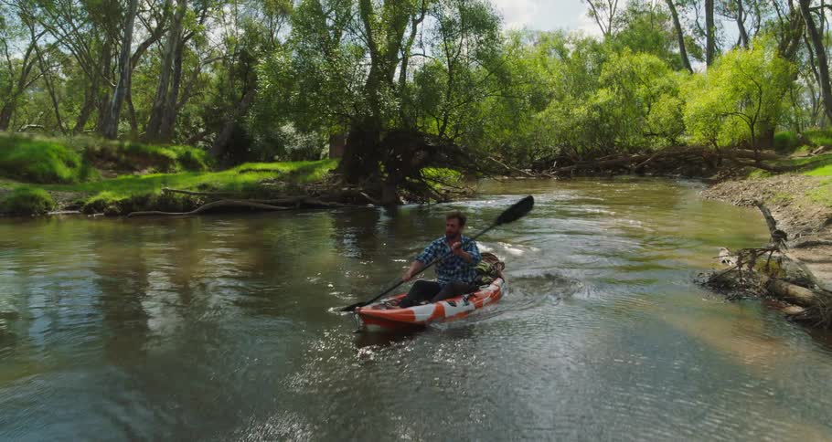 Man paddles canoe down river in wilderness