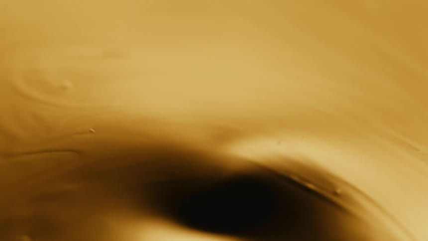 Ripples run through a molten gold liquid