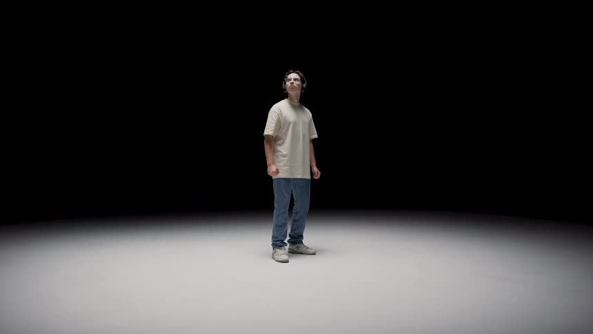 There is a young teenage boy that is standing and wearing headphones