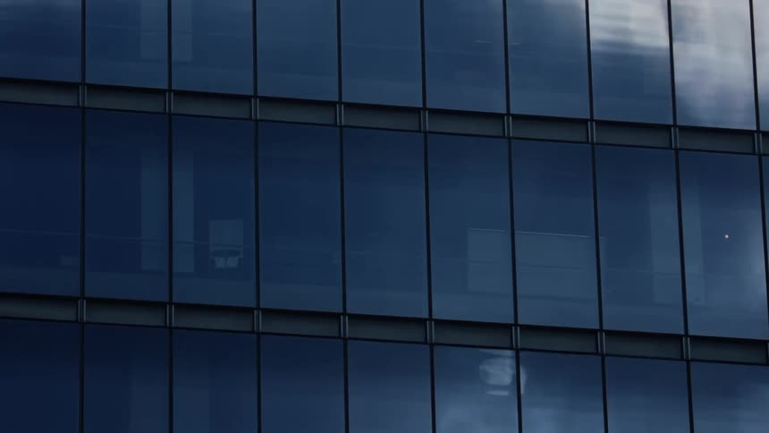 Reflections of clouds move across the windows of a building