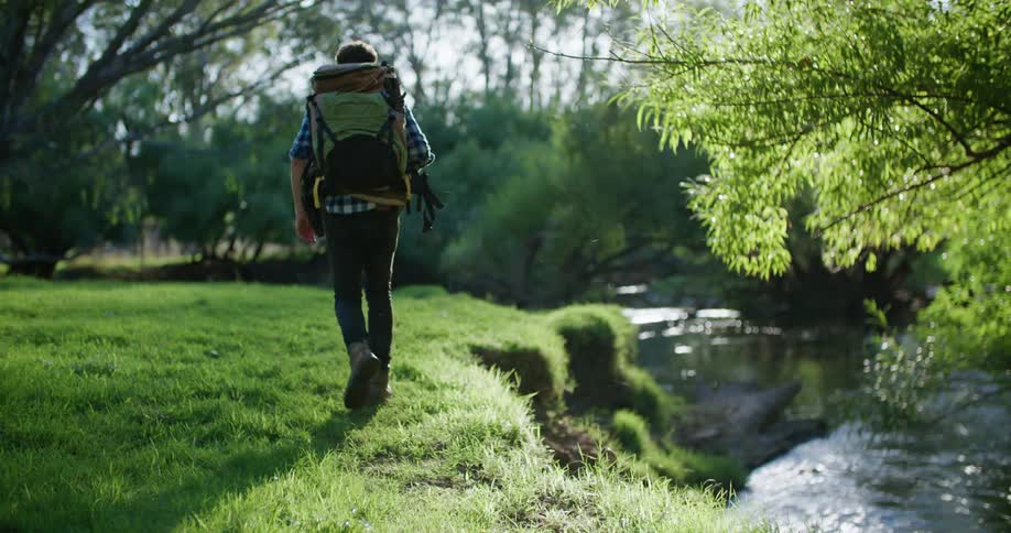 A young white man is hiking outside in the forest area