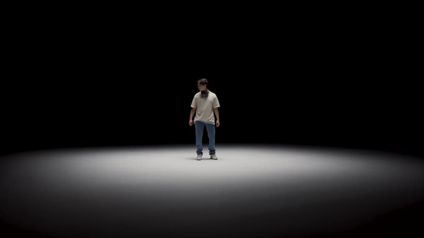 There is a young white man that is standing and looking around the room