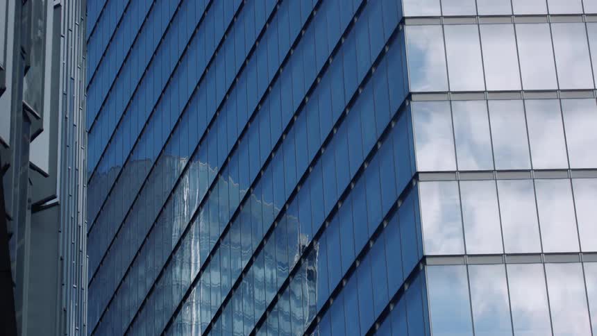 Reflection of the blue sky and buildings in the city skyline on the glass facade of a skyscraper
