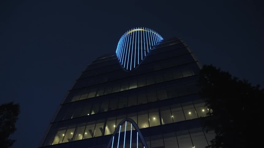 Lights glow in the darkness as a building with amazing architecture stands tall in the night sky