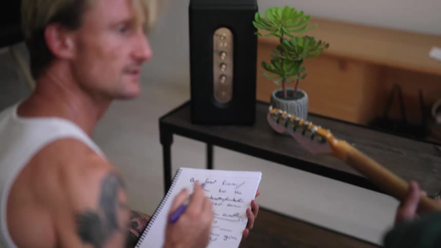 Two male musicians collaborate writing a song