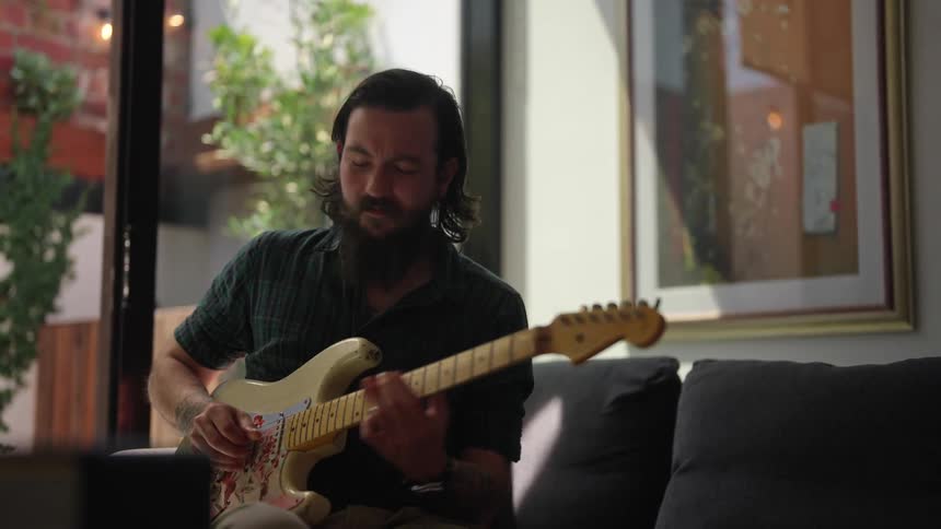 A man playing electric guitar in a room