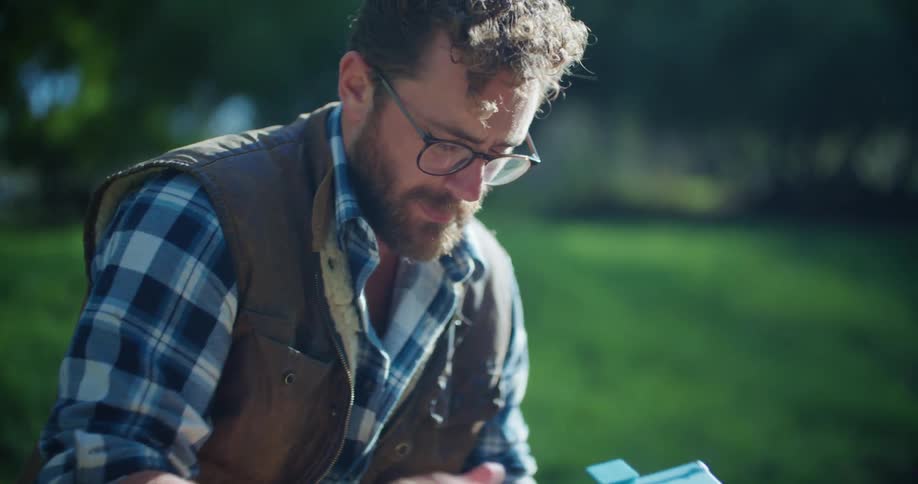 Man with glasses takes kit out of his bag while kneeling outdoors
