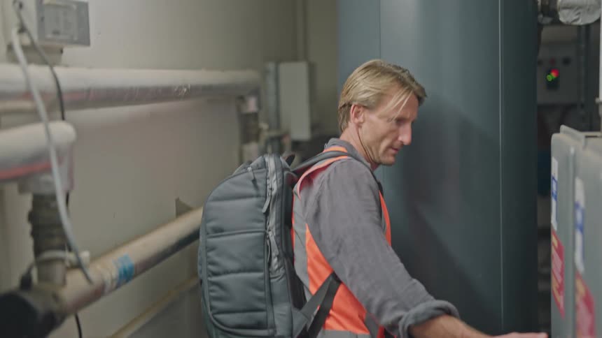 A man wearing a backpack is walking in a building