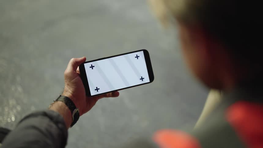 A young man is sitting down on the ground and looking at his phone