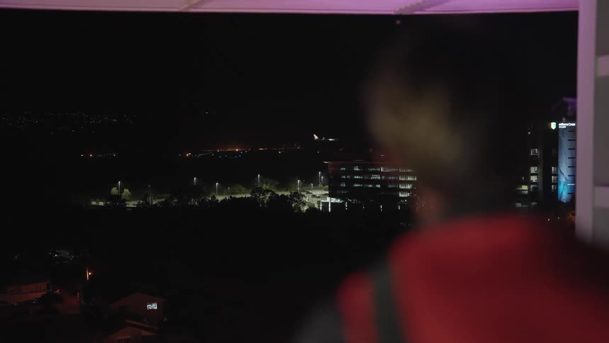 Man watching airplane land from building rooftop at night