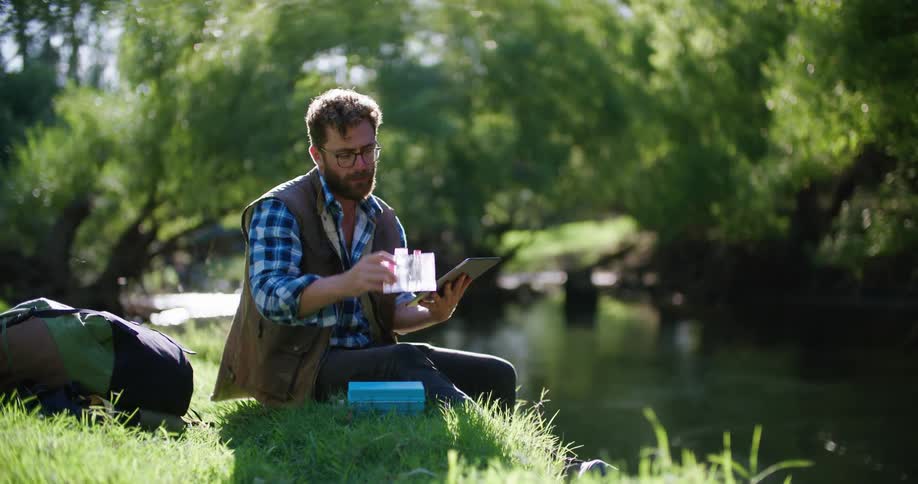 There is a younger man sitting on the grass outdoors in the day time
