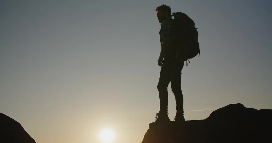 A young man is hiking and is standing on a cliff