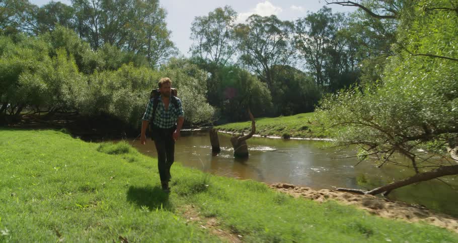 A man is hiking past the stream