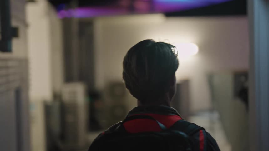 There is a young man that is walking ouside at night time