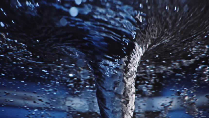 Light shines on bubbles as they swirl around water tornado vortex as it twists and turns in rotation