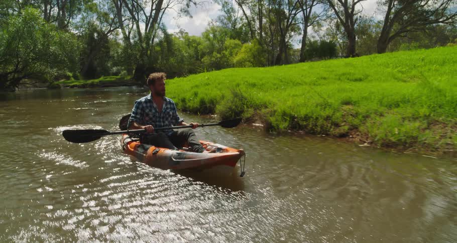 Man kayaking through narrow river in the wilderness