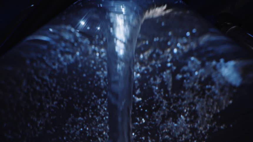 A vortex of clear blue liquid is twisting rapidly down the middle with tiny bubbles floating all around