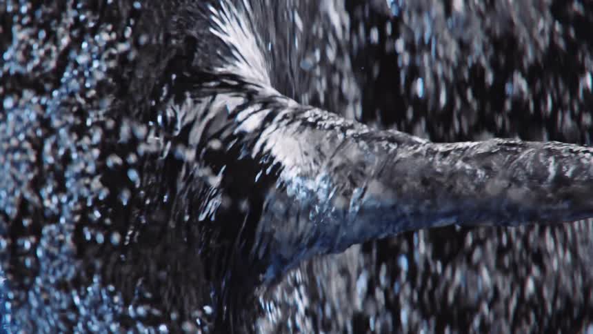 Light shines on a water tornado vortex as it twists and spins and bubbles move in the current