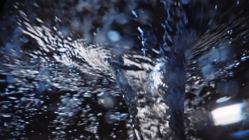 A funnel of crystal clear water swirls and creates ripples and bubbles