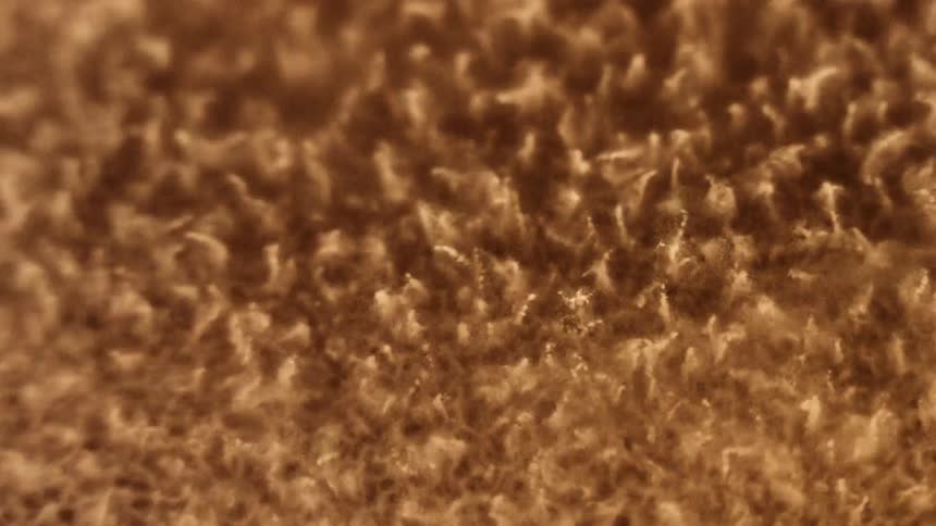 A gold liquid is vibrating and splashing then it melts down to a smooth surface