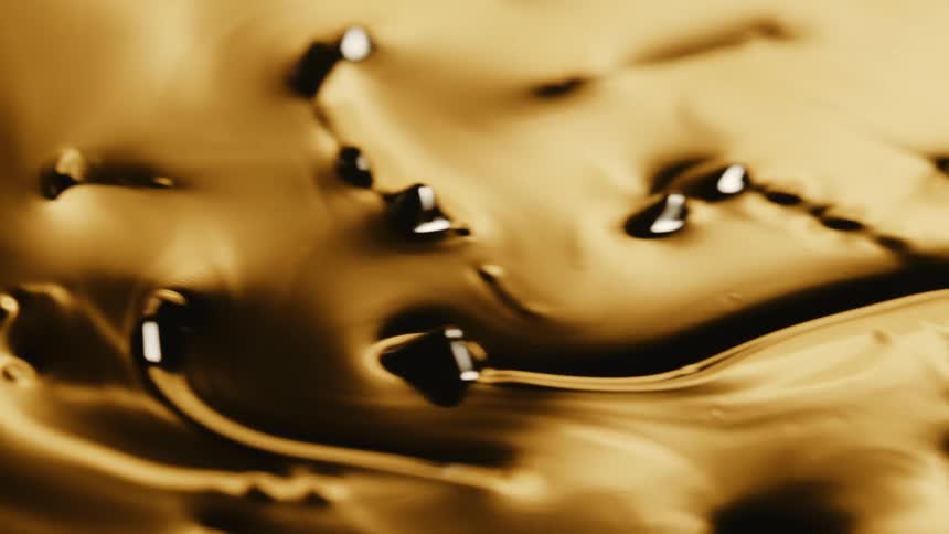 Gold liquid with dark beads moves from right to left