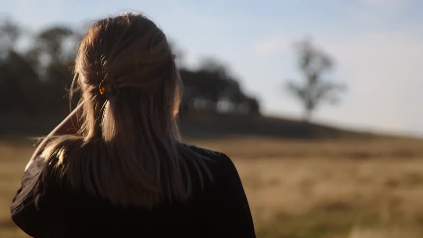 The view is of a young woman that is walking outdoors in the day time