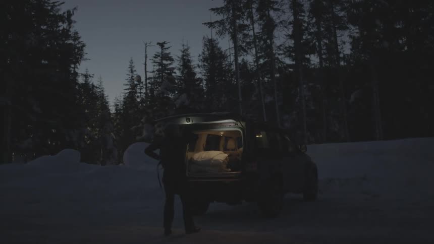 Woman getting backpack out of her vehicle at dusk