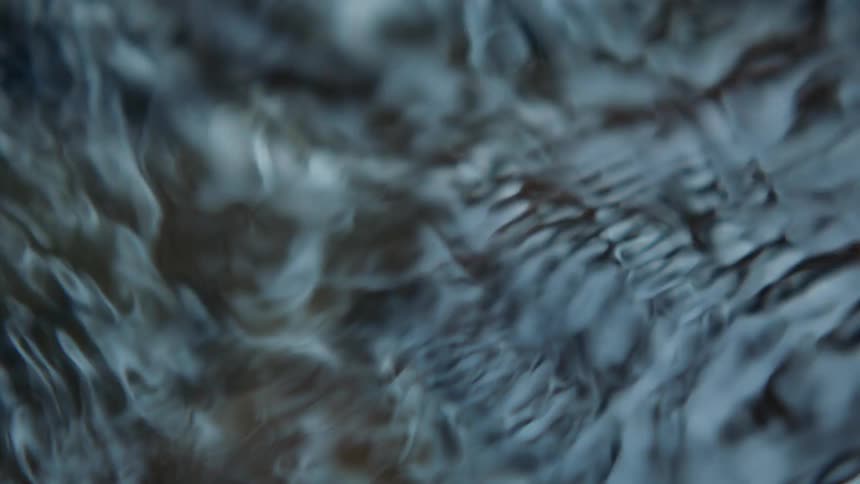 Close up of ripples and small waves criss crossing on the surface of shallow water