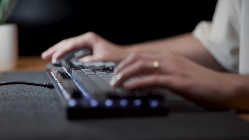 A man is sitting at a table typing on a computer keyboard