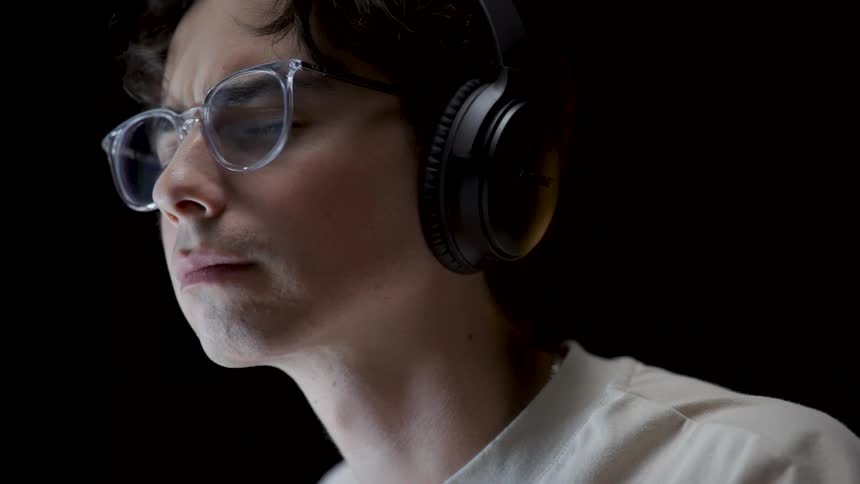 A young teenager boy is wearing headphones and listening to music