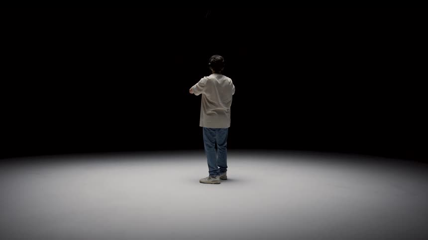 A young teenage boy is standing inside of a room