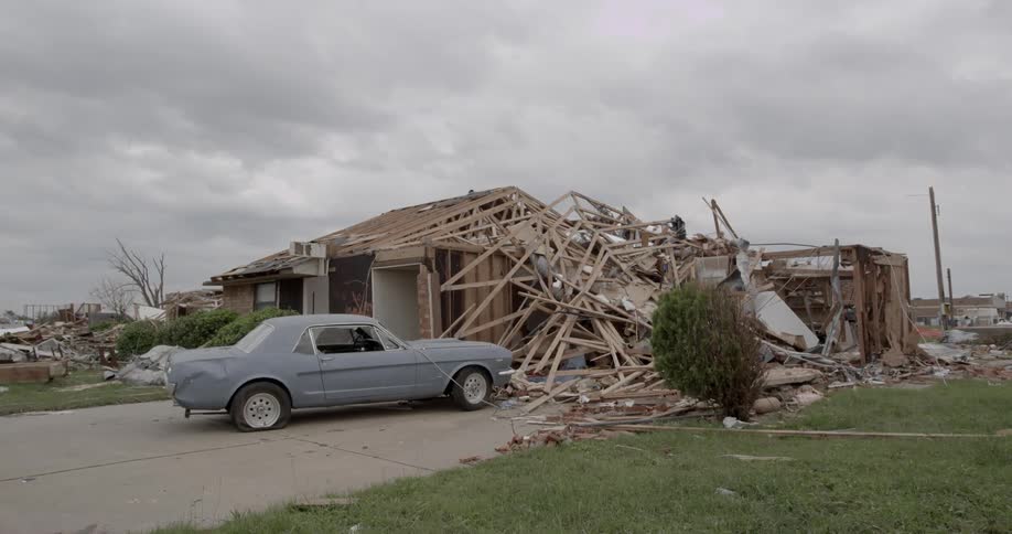 A car is parked in front of a destroyed house